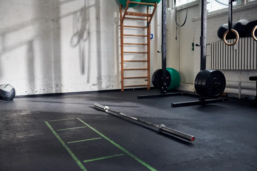 Trainingsfläche von CrossFit Icke mit Langhantel auf dem Boden, Rack, Sprossenwand und Turnringen